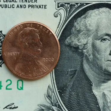 A penny placed on top of a U.S. ten-dollar bill, shown in close-up for size comparison.
