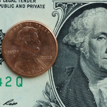 A penny placed on top of a U.S. ten-dollar bill, shown in close-up for size comparison.