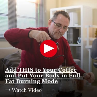 Add THIS to Your Coffee and Put Your Body in Full Fat Burning Mode Older man in a red sweater and glasses pouring an ingredient into his coffee at home