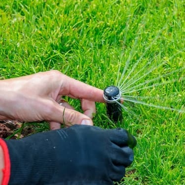 person adjusting a sprinkler
