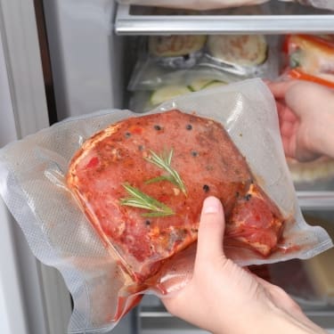 person puting vacuum sealing meat